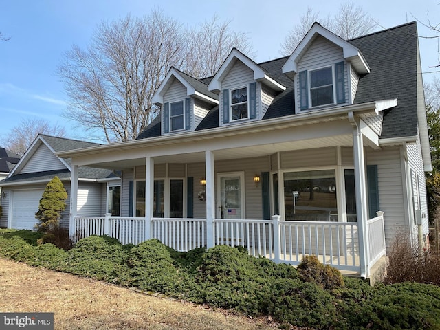 new england style home featuring covered porch, roof with shingles, and an attached garage