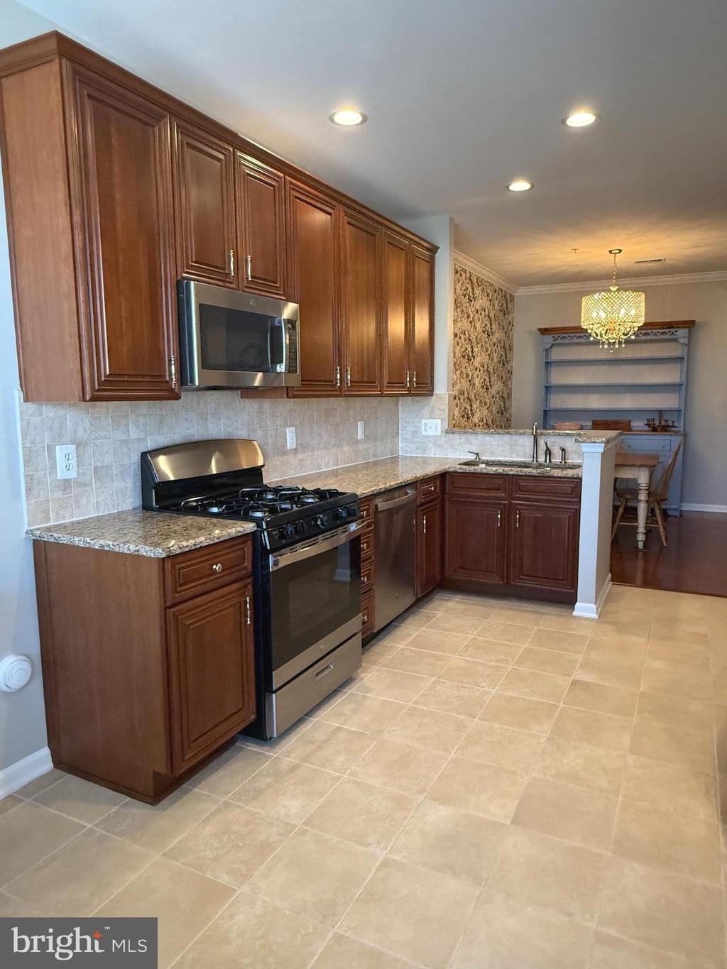 kitchen with stainless steel appliances, a sink, decorative backsplash, and light stone countertops