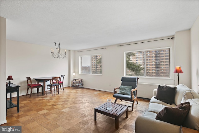 living area with a textured ceiling, baseboards, and an inviting chandelier