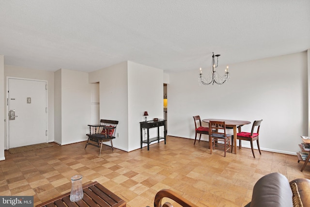 living room with baseboards, a notable chandelier, a textured ceiling, and light floors