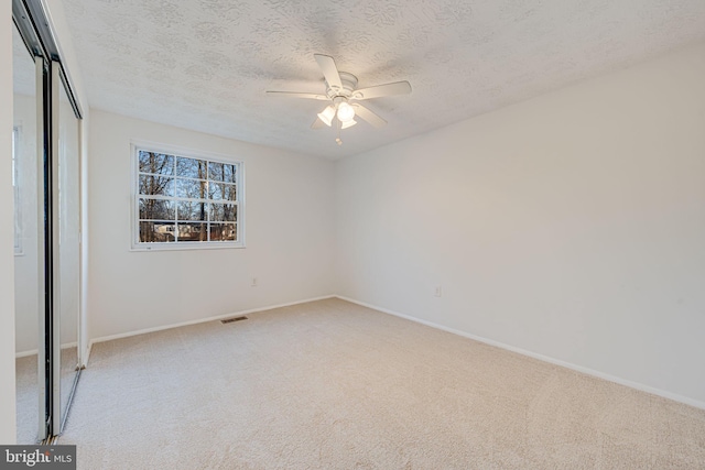 unfurnished bedroom featuring carpet floors, a closet, visible vents, and a textured ceiling