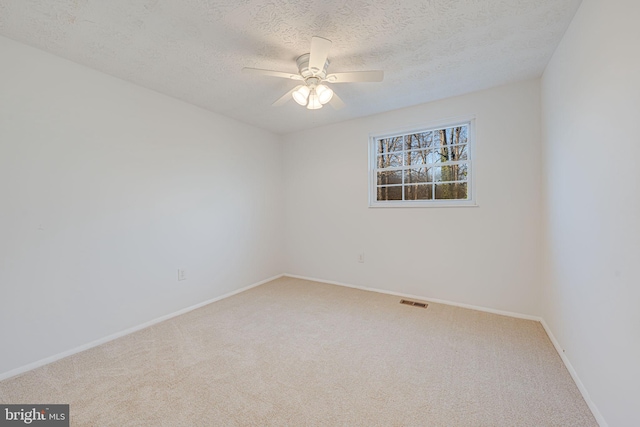 unfurnished room with ceiling fan, a textured ceiling, carpet, and visible vents