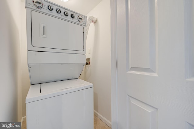 laundry area with baseboards, laundry area, and stacked washer / drying machine