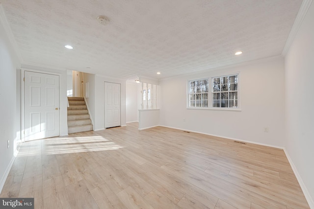 empty room featuring crown molding, a textured ceiling, stairs, and light wood-style floors