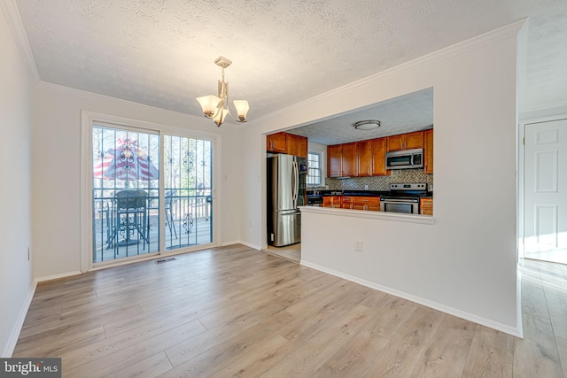 kitchen featuring appliances with stainless steel finishes, light wood-type flooring, brown cabinetry, and a notable chandelier