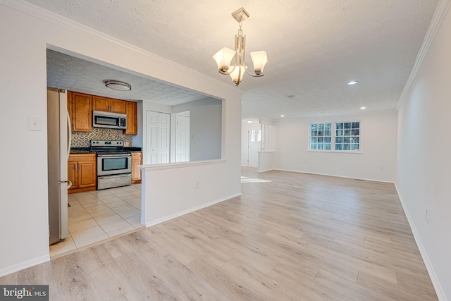 interior space with light wood-style floors, open floor plan, appliances with stainless steel finishes, brown cabinetry, and an inviting chandelier