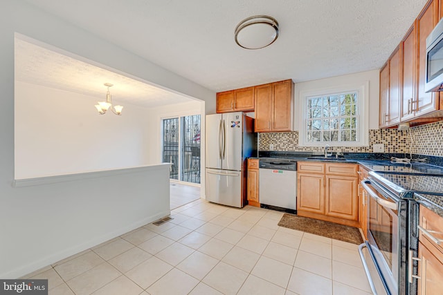 kitchen with stainless steel appliances, dark countertops, tasteful backsplash, visible vents, and a sink