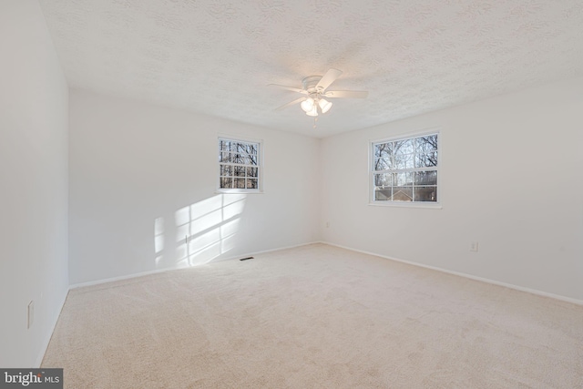 carpeted empty room featuring a ceiling fan and a textured ceiling