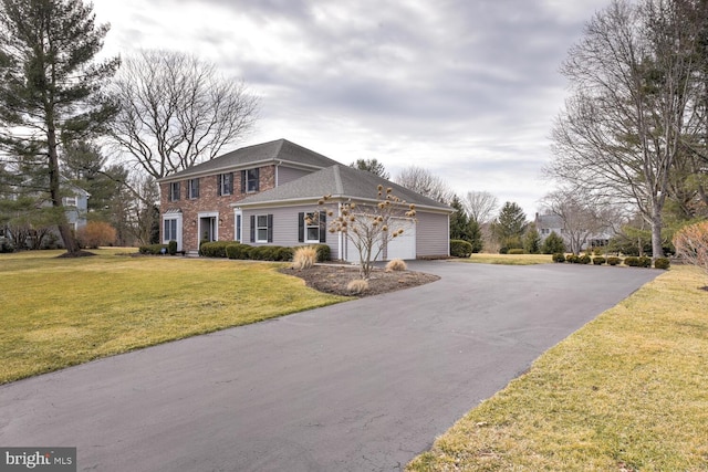 view of front of house with a garage, aphalt driveway, a front lawn, and brick siding