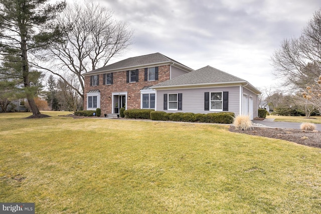 colonial home featuring a front yard, brick siding, an attached garage, and roof with shingles