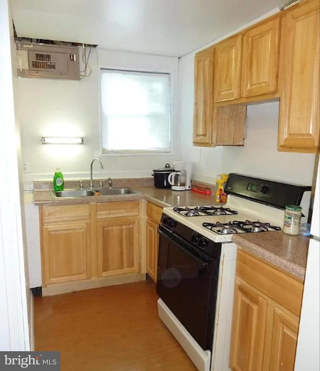 kitchen with light wood-type flooring, a sink, and gas range