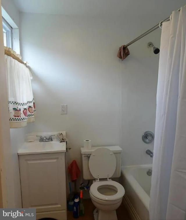 bathroom featuring a sink, shower / bathtub combination with curtain, and toilet