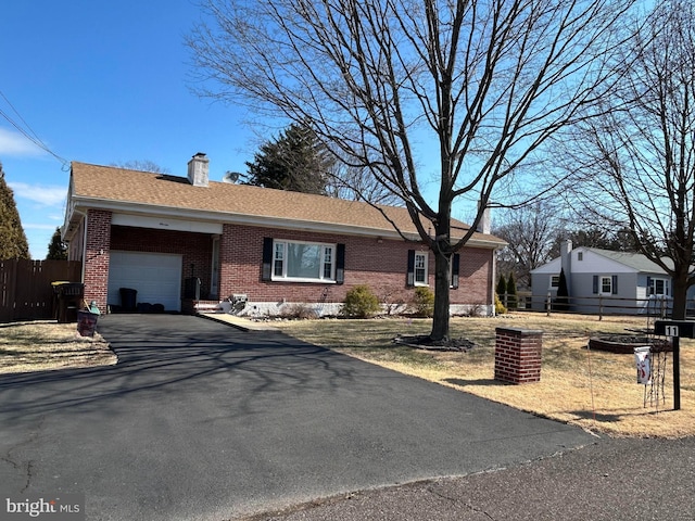 ranch-style home featuring driveway, fence, an attached garage, a shingled roof, and brick siding