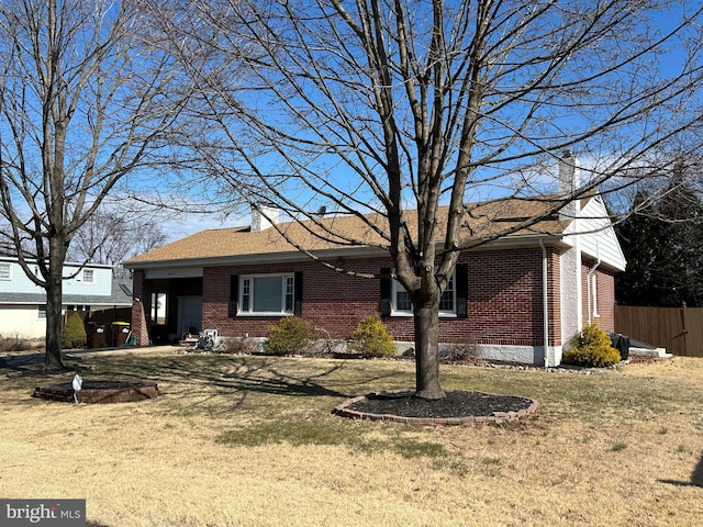 ranch-style house featuring brick siding, a chimney, a front yard, and fence