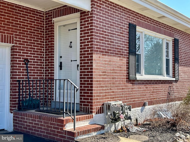 property entrance with an attached garage and brick siding