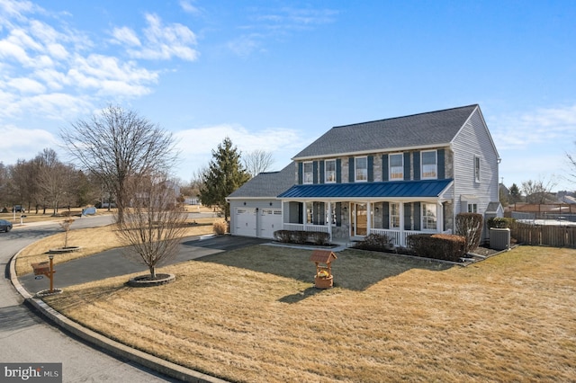 view of front of house featuring concrete driveway, covered porch, fence, a garage, and a front lawn