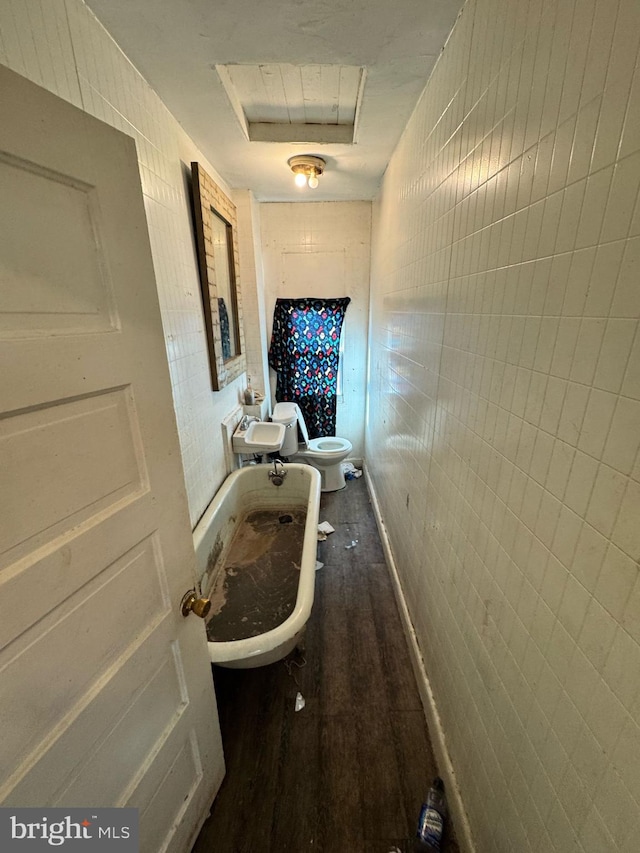 hall featuring a sink, attic access, dark wood finished floors, and tile walls