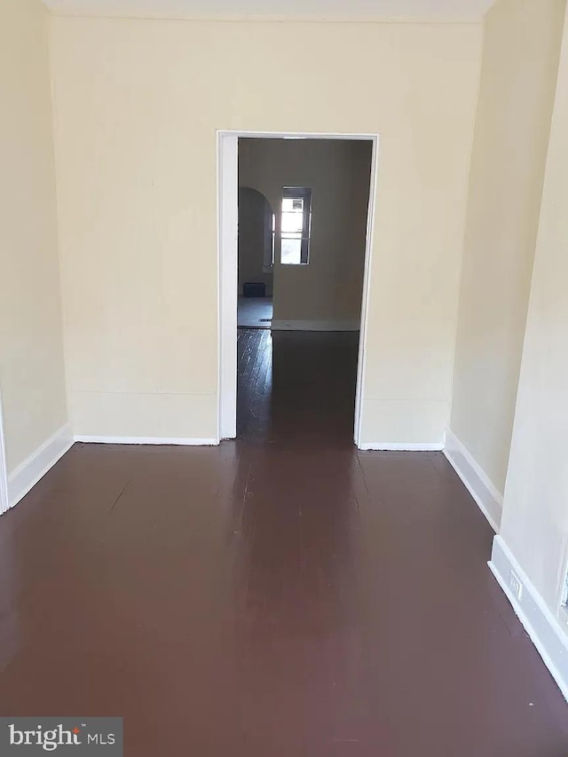 empty room with baseboards and dark wood finished floors