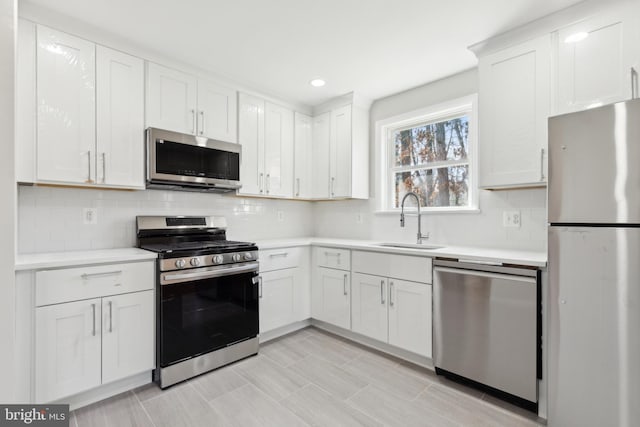 kitchen featuring a sink, light countertops, appliances with stainless steel finishes, white cabinetry, and tasteful backsplash