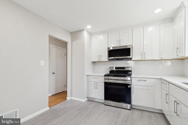 kitchen with visible vents, light countertops, decorative backsplash, appliances with stainless steel finishes, and white cabinetry