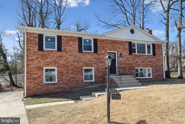 split foyer home with brick siding, a front lawn, and a chimney