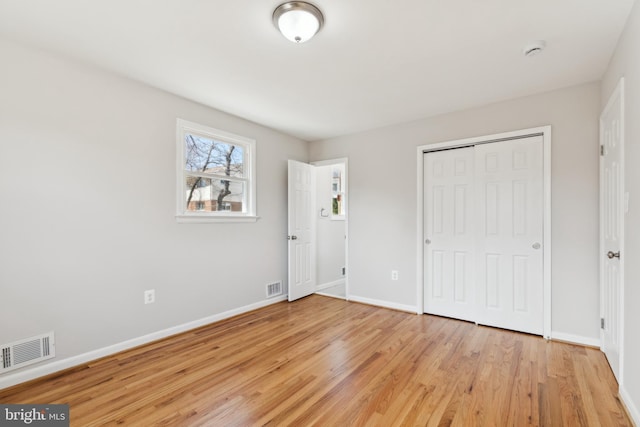 unfurnished bedroom featuring a closet, baseboards, visible vents, and light wood finished floors