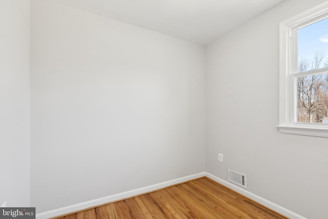 spare room featuring visible vents, light wood-style flooring, and baseboards