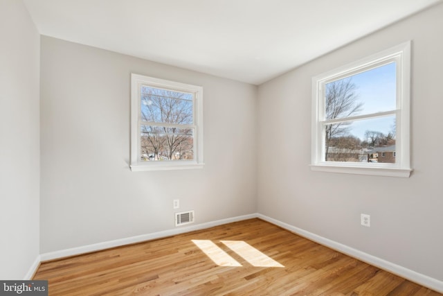 spare room with visible vents, baseboards, and wood finished floors