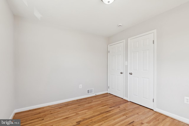 unfurnished bedroom featuring visible vents, light wood-type flooring, and baseboards