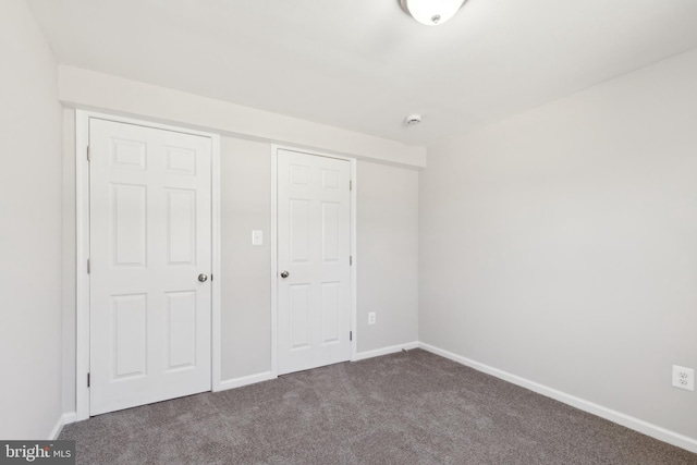 unfurnished bedroom with baseboards and dark carpet