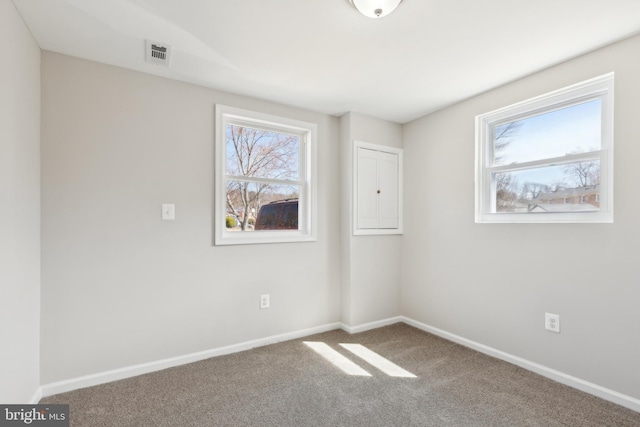 empty room with baseboards, visible vents, and carpet floors