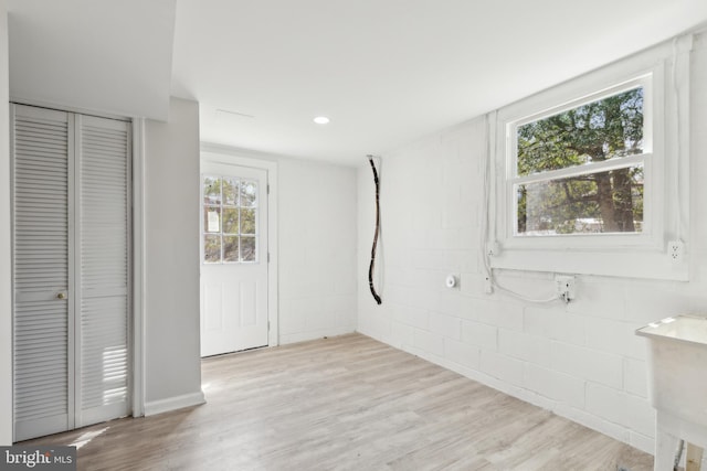 interior space with concrete block wall, recessed lighting, a sink, a closet, and light wood-type flooring