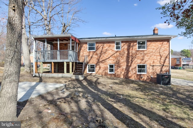 rear view of house with a chimney, stairs, a deck, central air condition unit, and brick siding