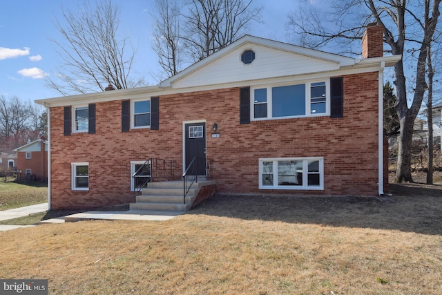 split foyer home with a front lawn, brick siding, and a chimney