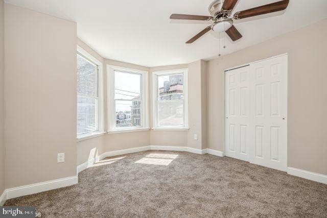 unfurnished bedroom featuring ceiling fan, carpet floors, a closet, and baseboards