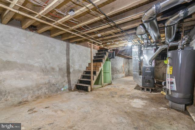 unfinished below grade area featuring heating unit, water heater, and stairway