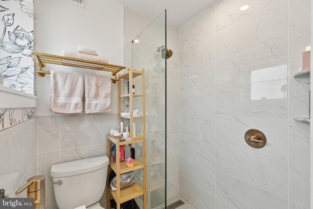 bathroom featuring walk in shower, toilet, and tile walls