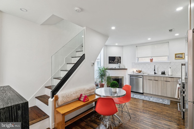 kitchen featuring dark wood finished floors, recessed lighting, backsplash, a sink, and dishwasher