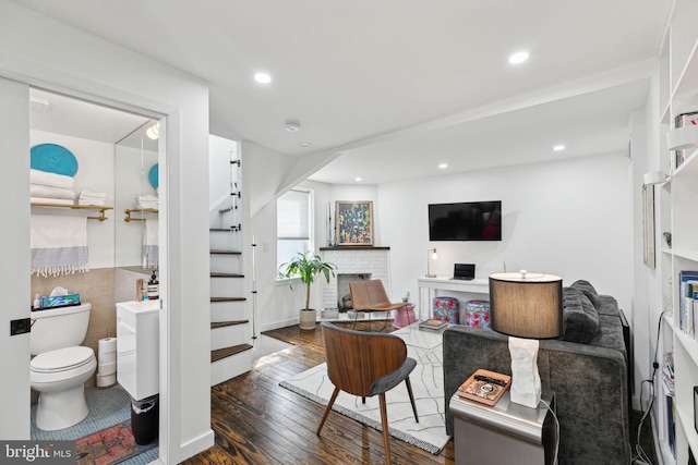 living room with stairs, recessed lighting, a brick fireplace, and hardwood / wood-style flooring