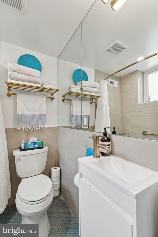 bathroom featuring toilet, visible vents, and tile walls