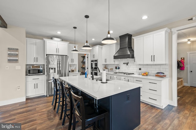 kitchen featuring dark wood finished floors, custom exhaust hood, stainless steel appliances, backsplash, and a sink