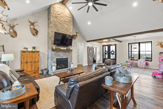 living area with beam ceiling, french doors, a stone fireplace, wood finished floors, and high vaulted ceiling