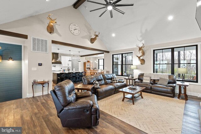 living area with dark wood-type flooring, visible vents, beamed ceiling, and high vaulted ceiling