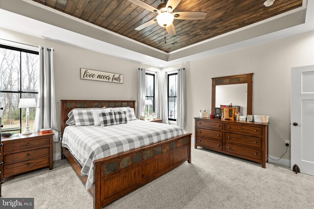 carpeted bedroom with wood ceiling, a raised ceiling, and a ceiling fan