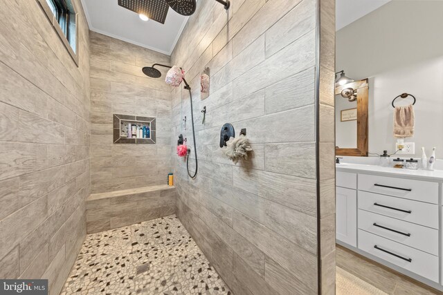 full bathroom with ornamental molding, a tile shower, and vanity