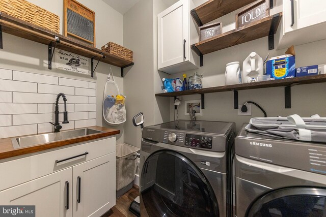 laundry room with dark wood finished floors, washer and clothes dryer, a sink, and cabinet space