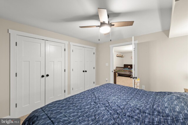 bedroom with ceiling fan, carpet flooring, and two closets