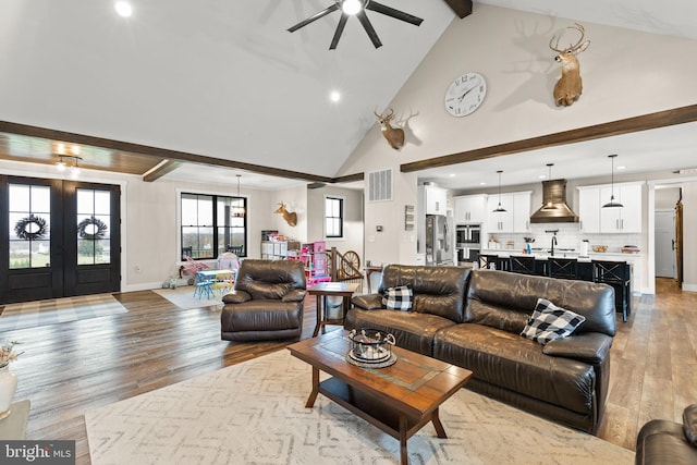 living room featuring baseboards, visible vents, beamed ceiling, wood finished floors, and high vaulted ceiling