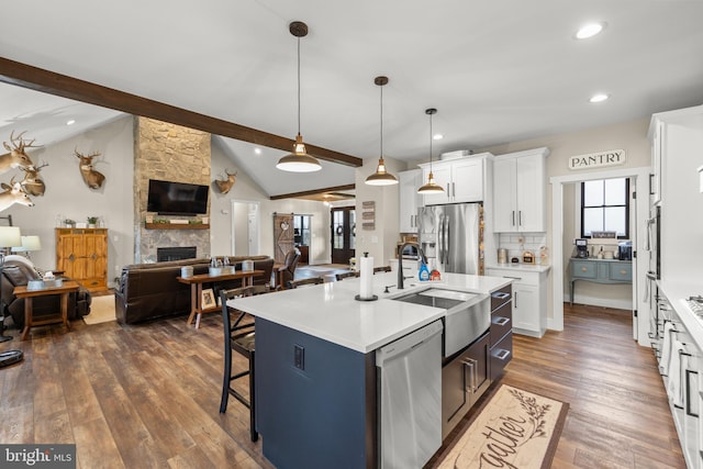 kitchen with vaulted ceiling with beams, a breakfast bar area, stainless steel appliances, open floor plan, and a sink