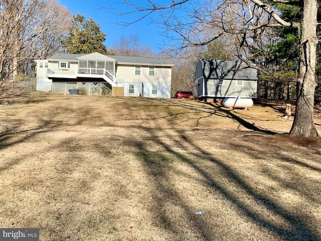 rear view of house featuring a sunroom, an outdoor structure, and a shed